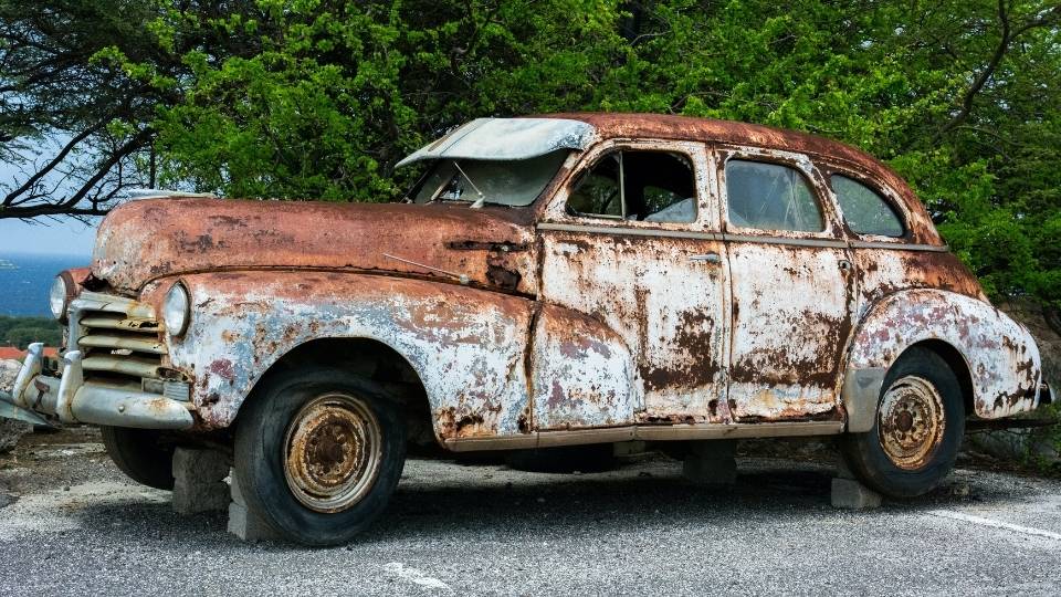 Rusty antique car on cinder blocks